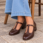 Detalle de los zapatos Maddalena marrón con vaqueros, sentada en una terraza