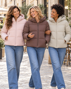 Tres amigas con chaquetas puffer en rosa, marrón y tono claro